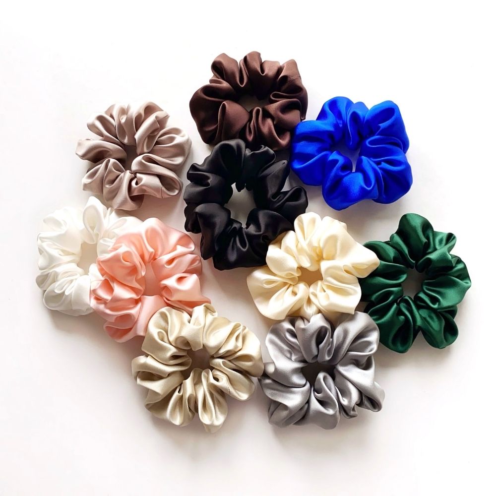 Assorted colorful mulberry silk satin scrunchies and hair ties on a white background