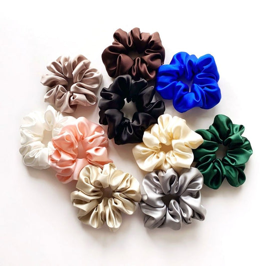 Assorted colorful mulberry silk satin scrunchies and hair ties on a white background