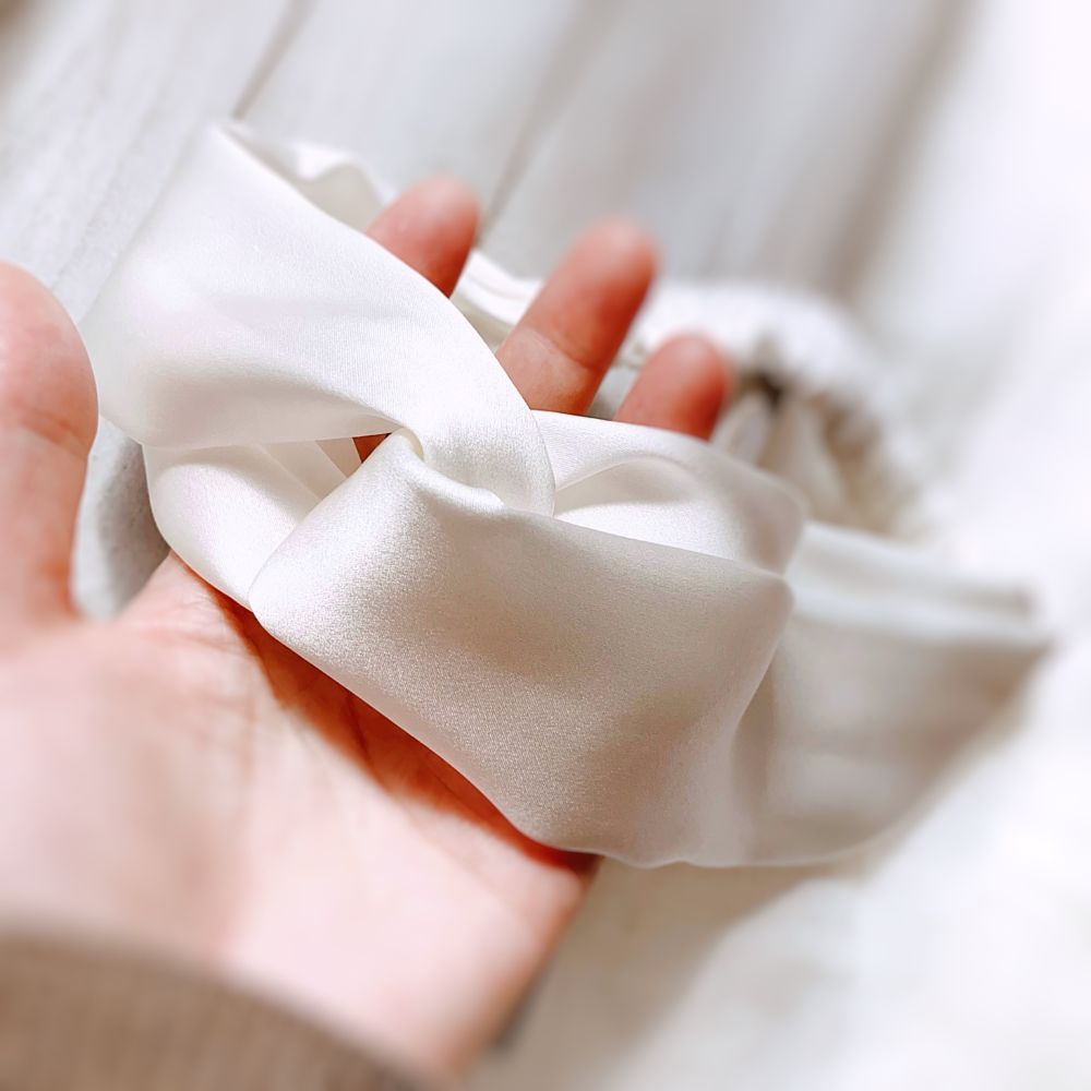 A close-up of a twisted white mulberry silk satin headband 