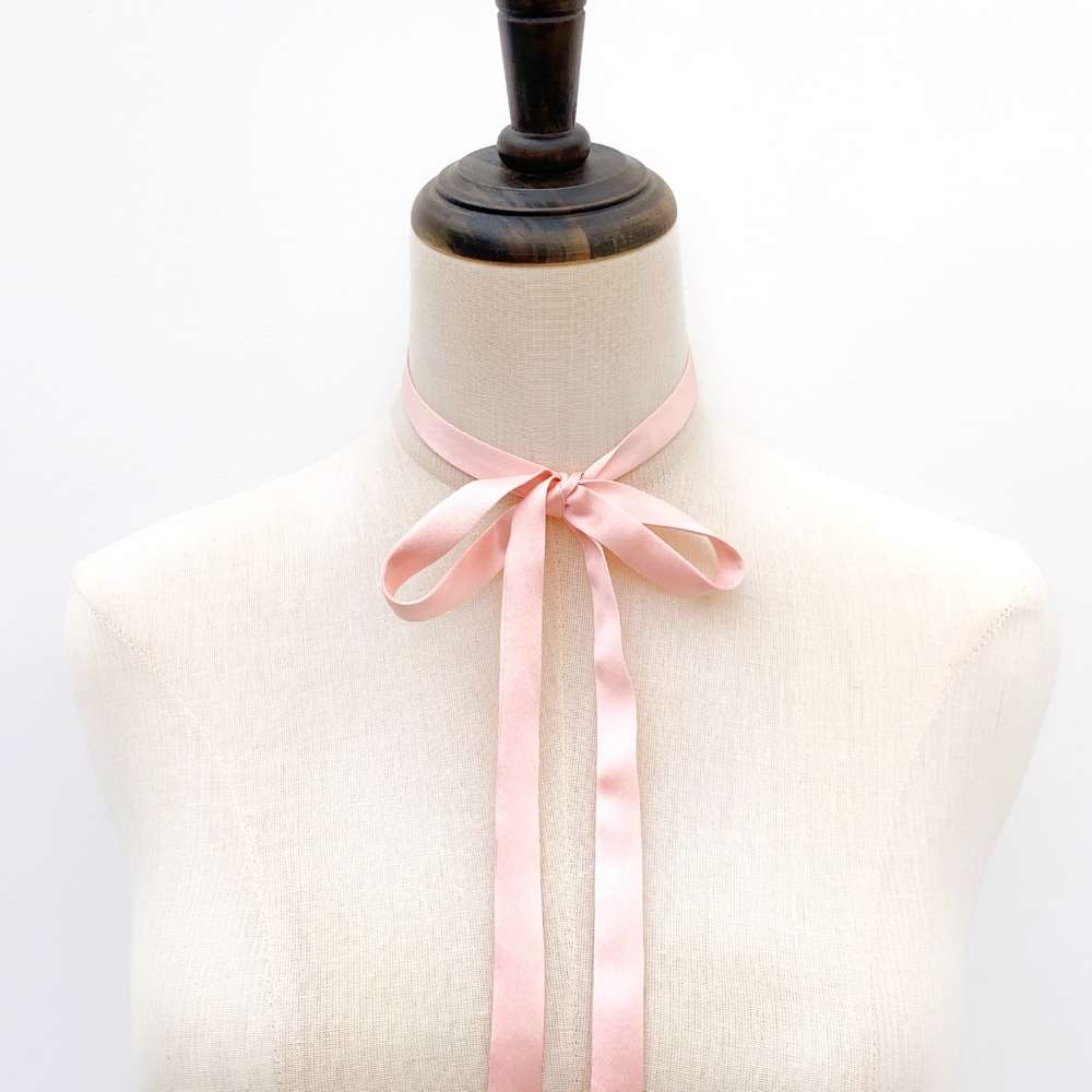 Mannequin wearing a light pink mulberry silk satin ribbon scarf against a white background
