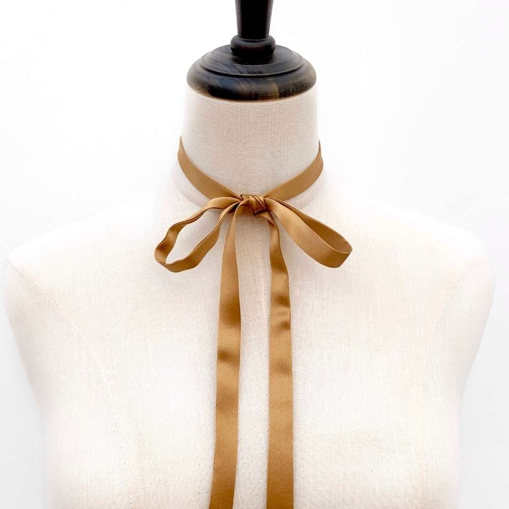 Mannequin wearing a Copper brown ultra skinny mulberry silk scarf tied into a bow on a white background