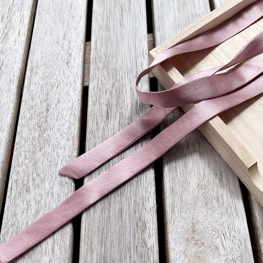 muted purple mulberry silk satin ribbon on a wooden surface