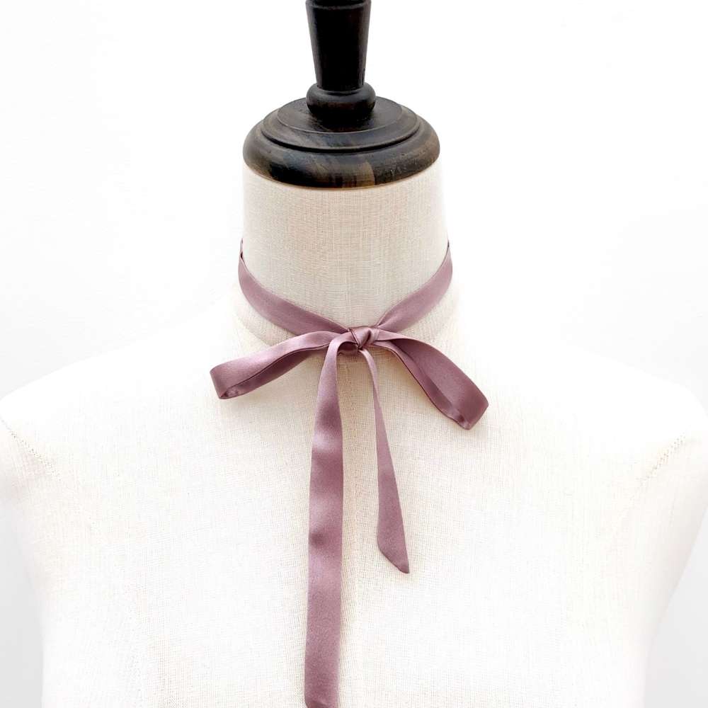 Mannequin wear a muted purple mulberry silk satin ribbon bow on a white background