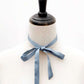Mannequin with a dusty blue mulberry silk ribbon necktie tied around its neck on a white background