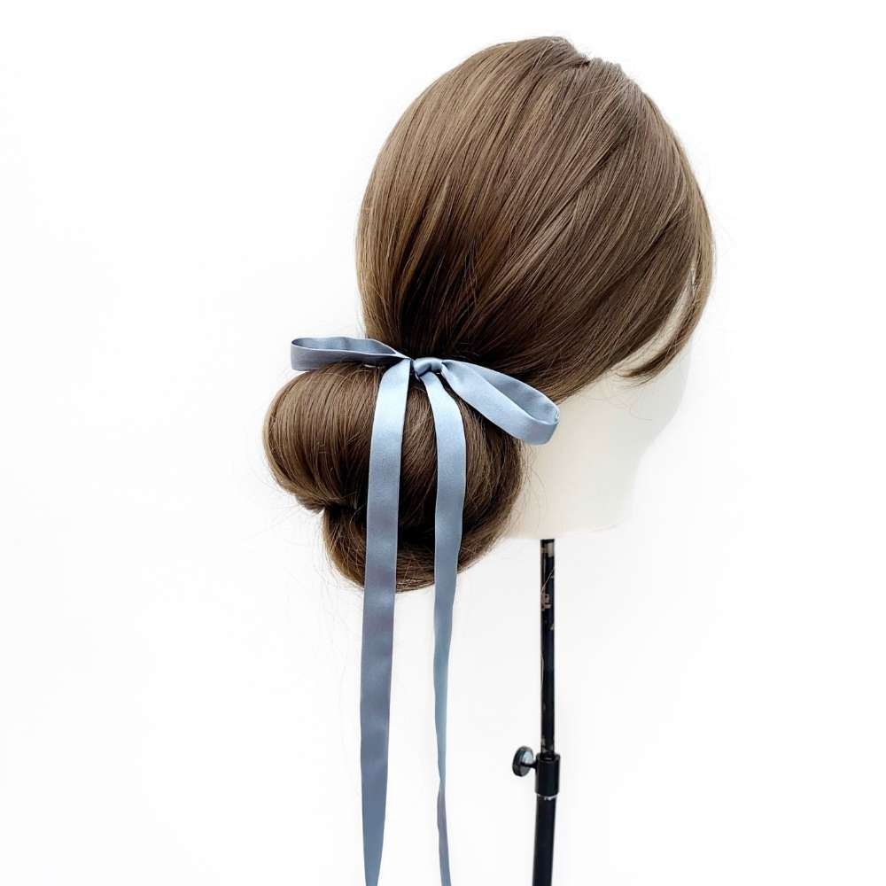 Mannequin head with brown hair styled in a bun with a ultra skinny dusty blue mulberry silk hair tie on a white background