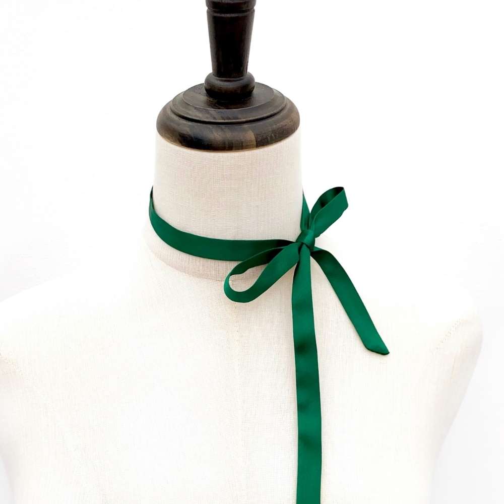Mannequin with forest green mulberry silk satin ribbon scarf tied around its neck on a white background