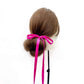 Mannequin head with brown hair styled in a bun with a hot pink ultra skinny mulberry silk hair tie on a white background