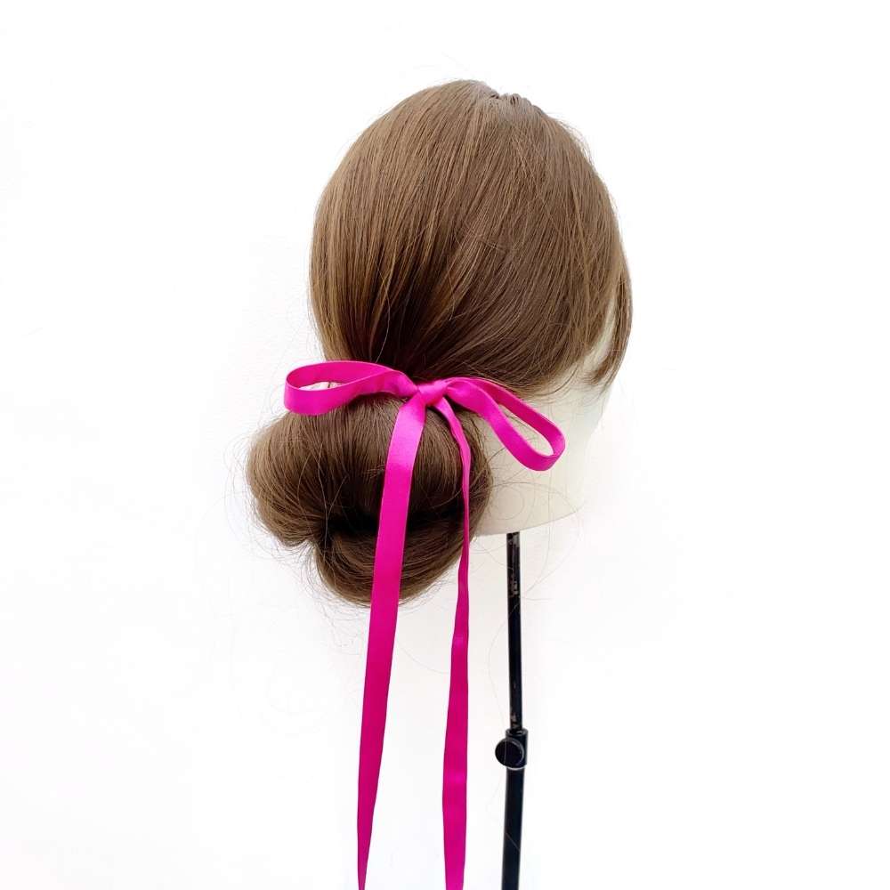 Mannequin head with brown hair styled in a bun with a hot pink ultra skinny mulberry silk hair tie on a white background