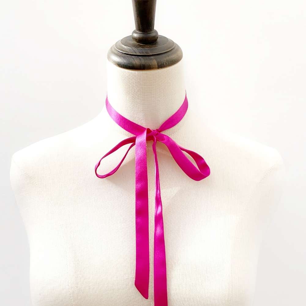 Mannequin wearing a bright pink mulberry silk ribbon necktie scarf on a white background