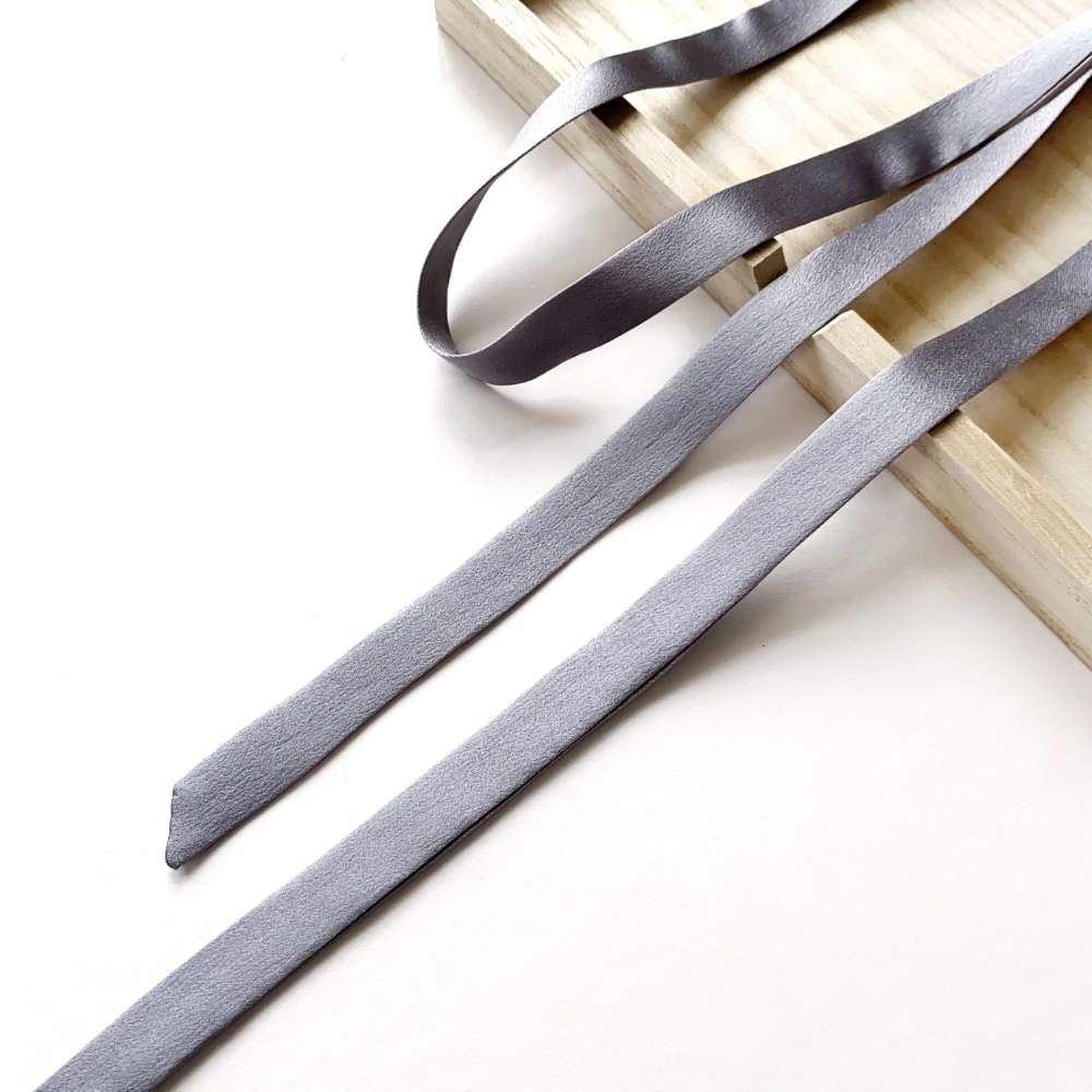 Gray mulberry silk satin ribbon scarf on a wooden block with a white background