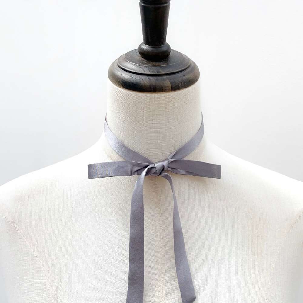 Mannequin wearing a gray mulberry silk skinny ribbon neck tie scarf against a white background