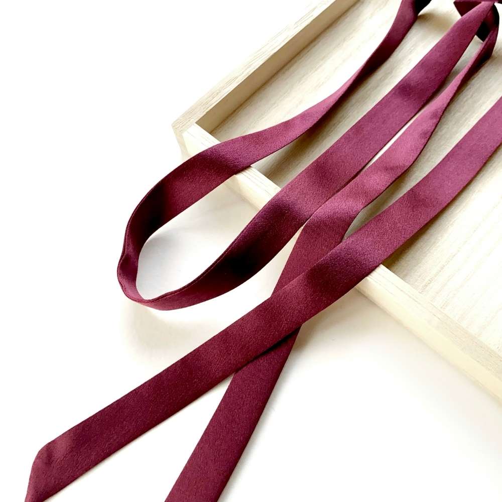Maroon mulberry silk satin ribbon on a white surface