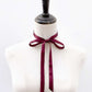 Mannequin with a burgundy mulberry silk satin ribbon tied around its neck on a white background
