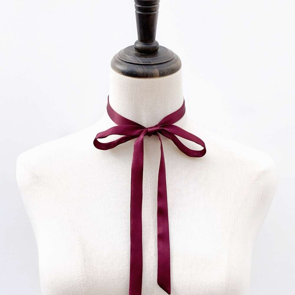 Mannequin with a burgundy mulberry silk satin ribbon tied around its neck on a white background
