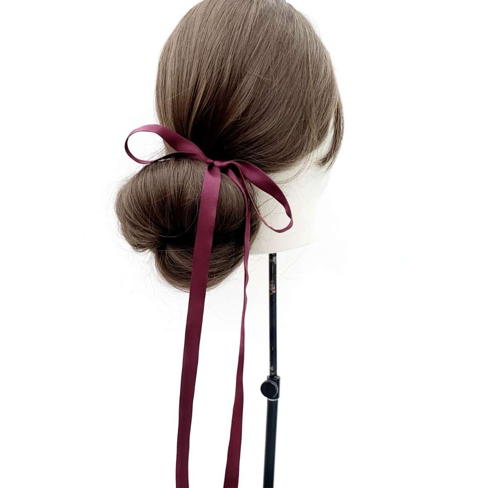 Mannequin head with brown hair styled in a bun with a burgundy mulberry silk satin hair ribbon on a white background