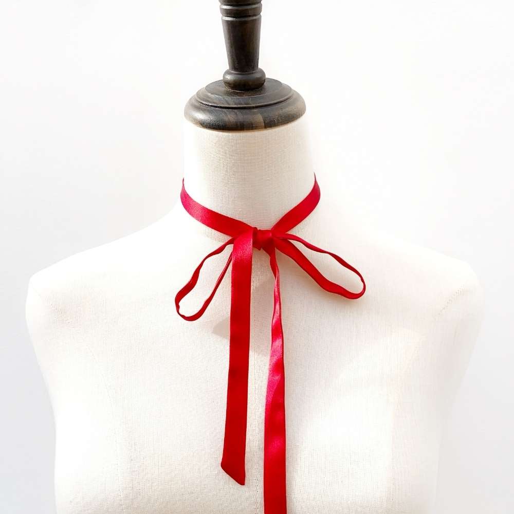 Mannequin with a red mulberry silk ribbon necktie tied around its neck on a white background