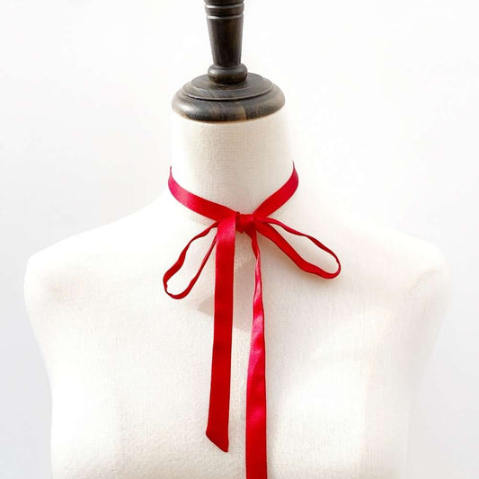 Mannequin with a red mulberry silk ribbon necktie tied around its neck on a white background