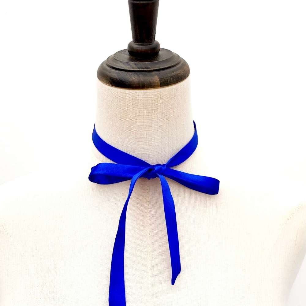 Mannequin with a royal blue silk satin ribbon scarf tied around its neck on a white background