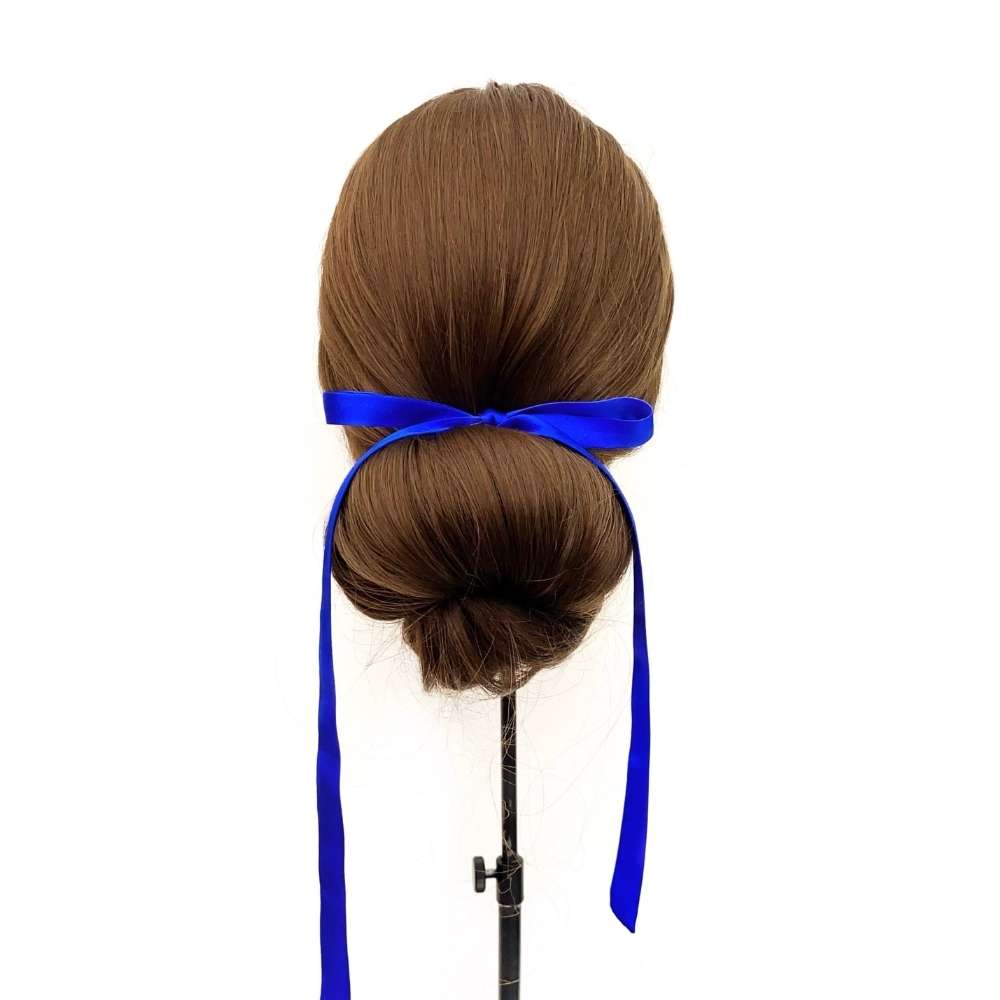 Mannequin head with brown hair styled in a bun and royal blue silk ribbon hair tie on a white background