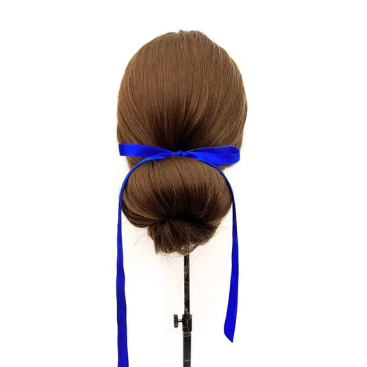 Mannequin head with brown hair styled in a bun and royal blue silk ribbon hair tie on a white background
