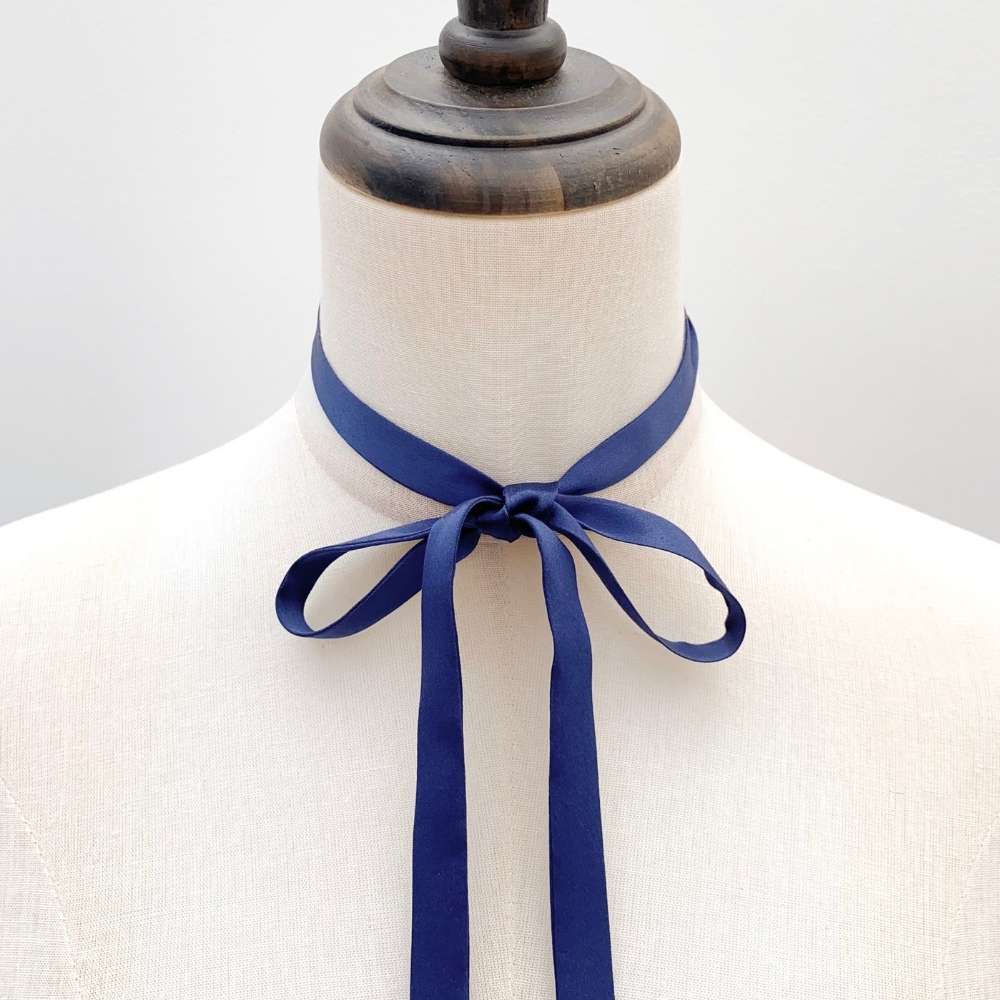 Mannequin wearing a sapphire blue silk ribbon neck scarf against a plain background