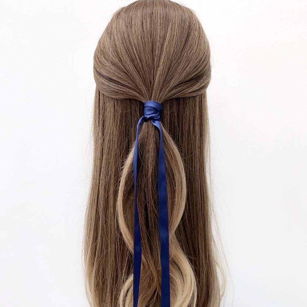 Long brown hair with a sapphire blue mulberry silk hair tie tied in a ponytail on a white background