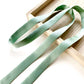 Seafoam green mulberry silk satin ribbon scarf on a wooden surface