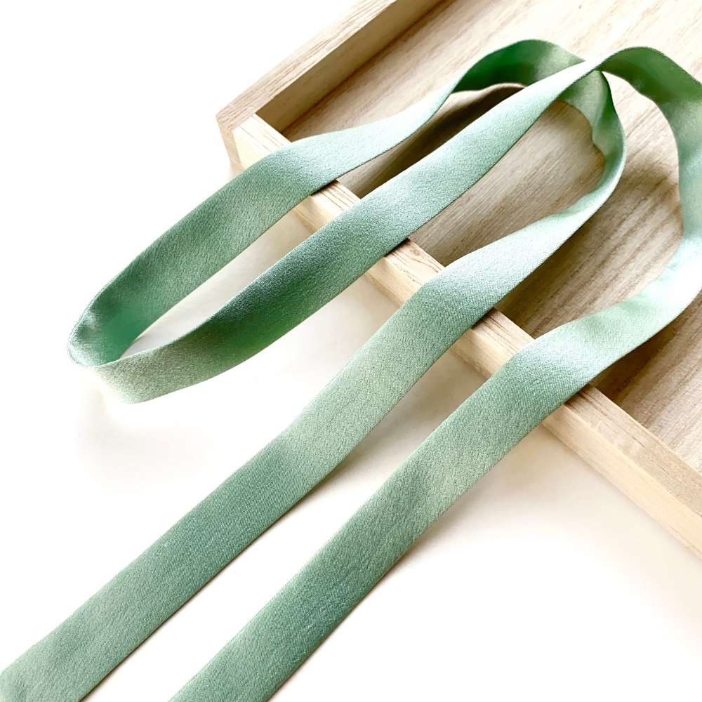 Seafoam green mulberry silk satin ribbon scarf on a wooden surface
