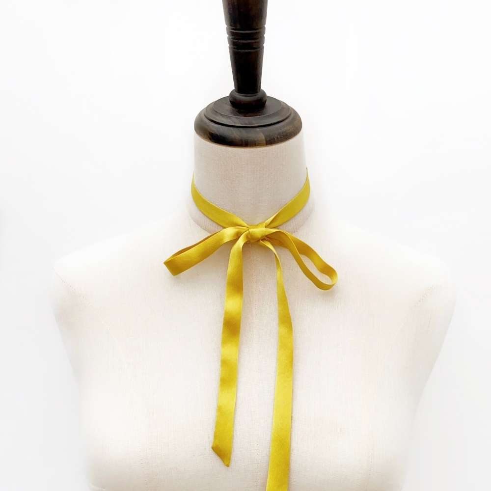 Mannequin with a Golden Yellow mulberry silk satin ribbon  scarf tied around its neck on a white background