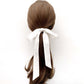 Hair tied in a ponytail with a white silk ribbon on a white background