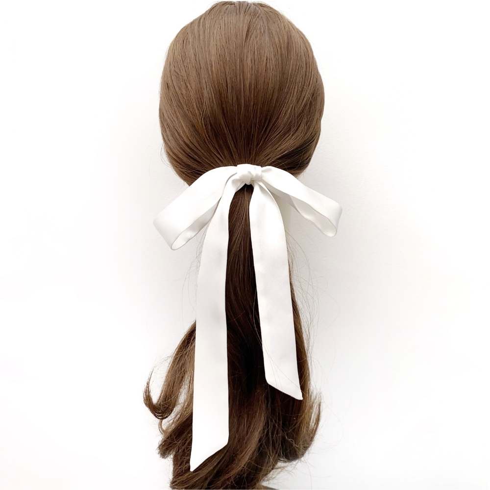 Hair tied in a ponytail with a white silk ribbon on a white background