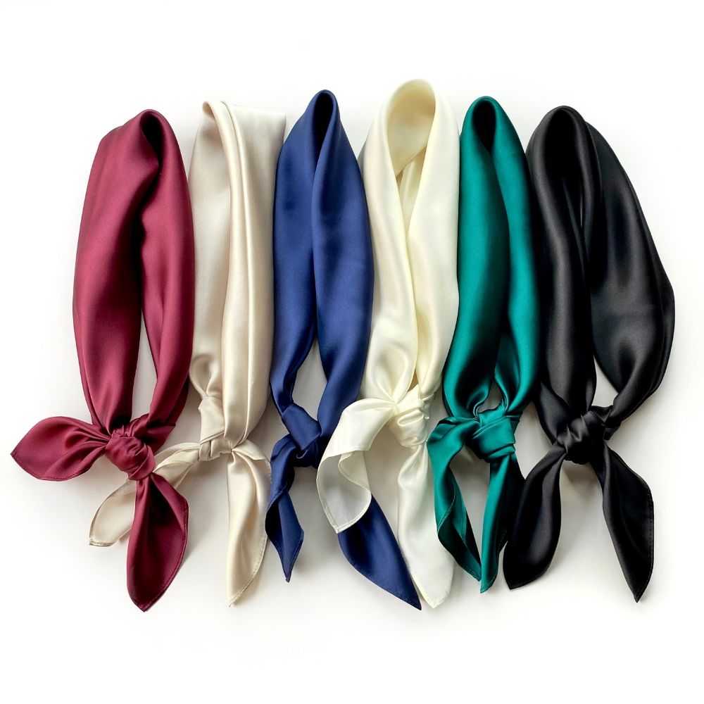 six plain mulberry silk square scarves in burgundy, light beige, navy blue, ivory, emerald green and black tied into the neckerchiefs on the white background