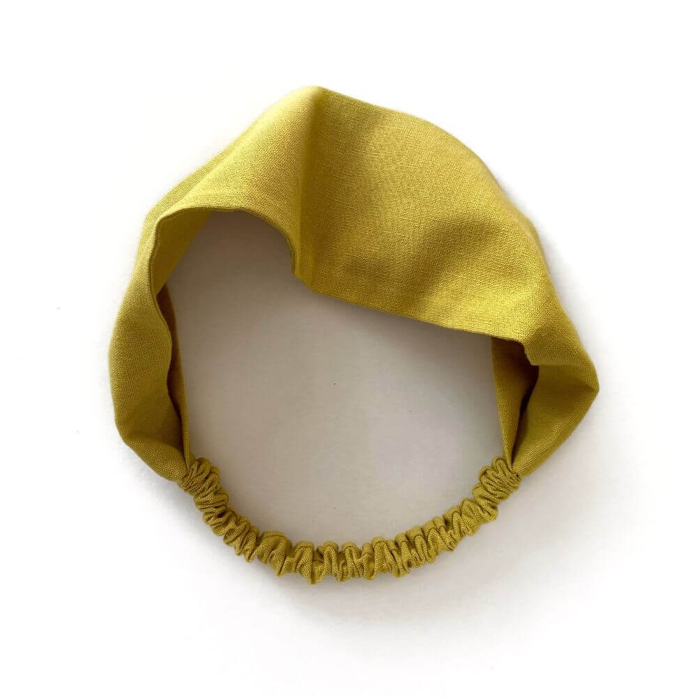 Mustard yellow linen headband on a white background