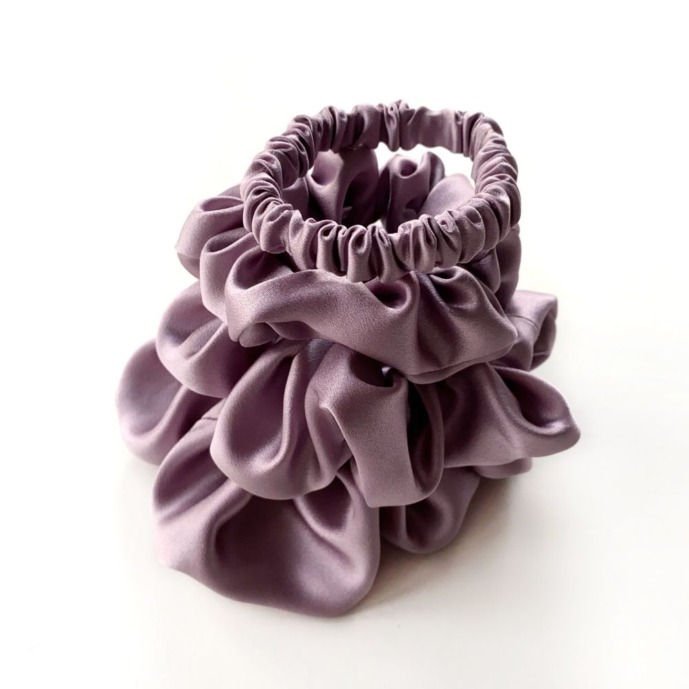 Set of purple pure mulberry silk satin scrunchies and hair ties on the white background.