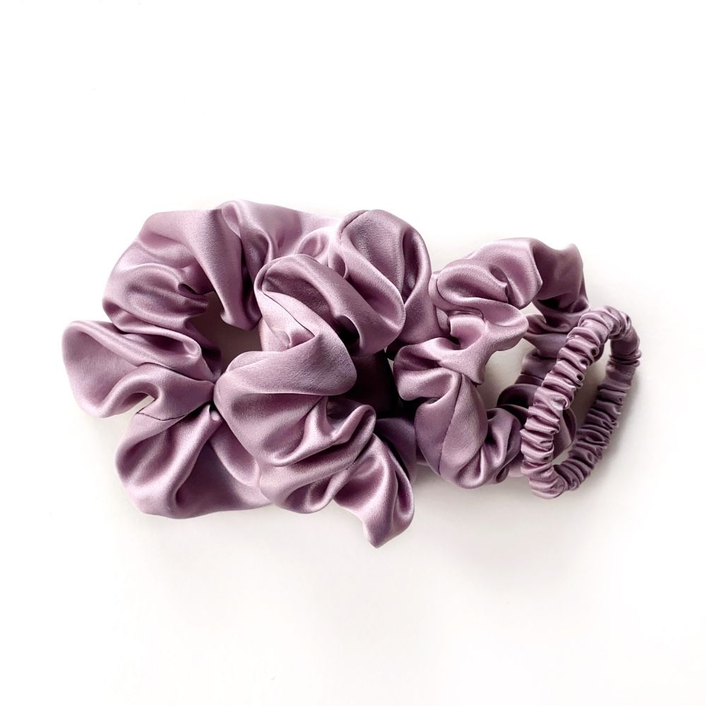 Set of purple pure mulberry silk satin scrunchies and hair ties on the white background.