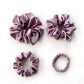 Set of purple pure mulberry silk satin scrunchies and hair ties on the white background.