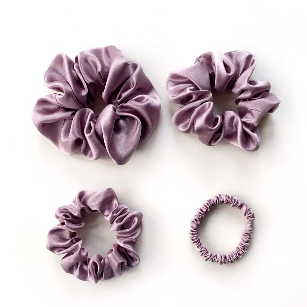 Set of purple pure mulberry silk satin scrunchies and hair ties on the white background.