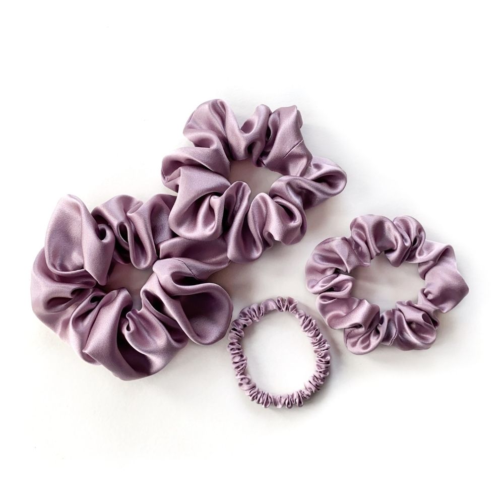 Set of purple pure mulberry silk satin scrunchies and hair ties on the white background.