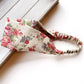 Natural Cotton Linen rose floral patterned headband on a light wooden surface