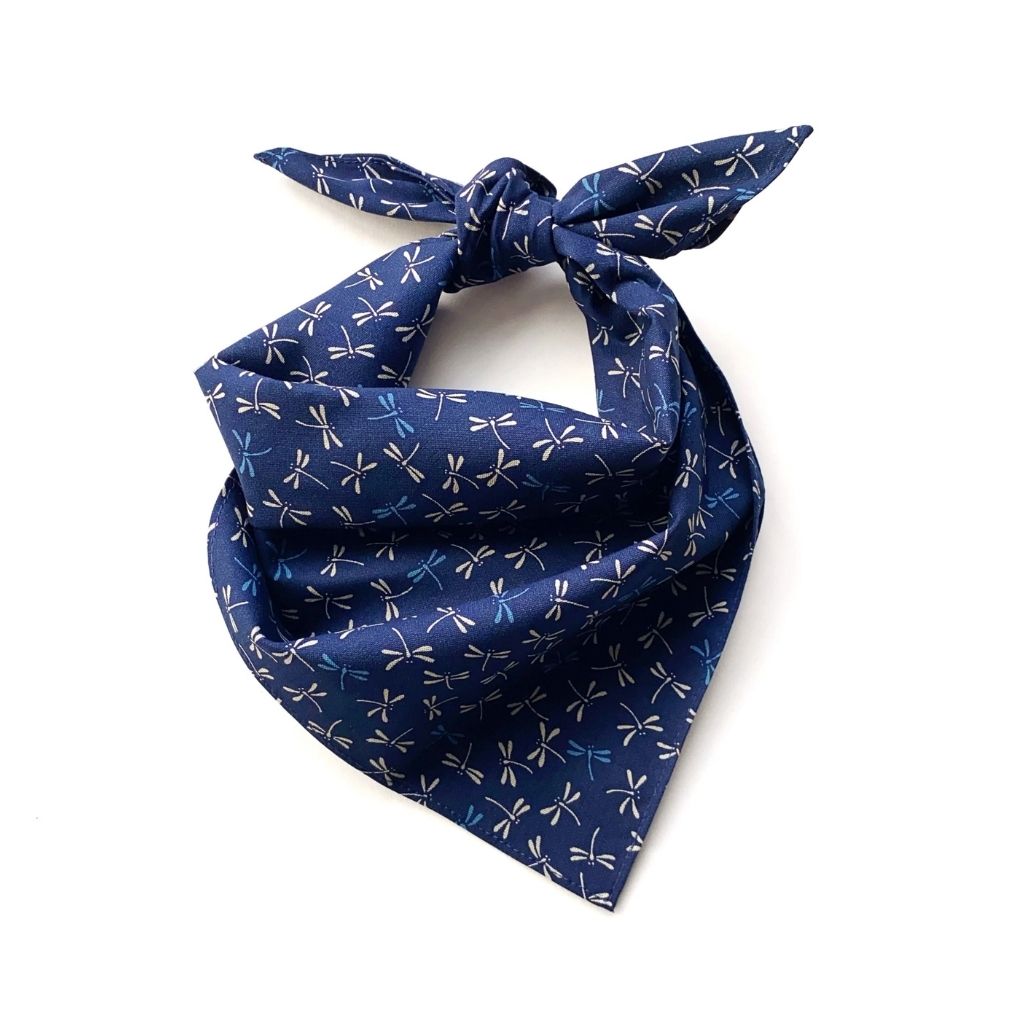 A A navy blue dragonfly print japanese cotton square neck scarf, tied in a knot at the top, shown on a plain white background.
