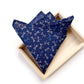A folded navy blue japanese cotton pocket square with a repeating dragonfly pattern in white and light blue, displayed inside a light wood tray on a white background.