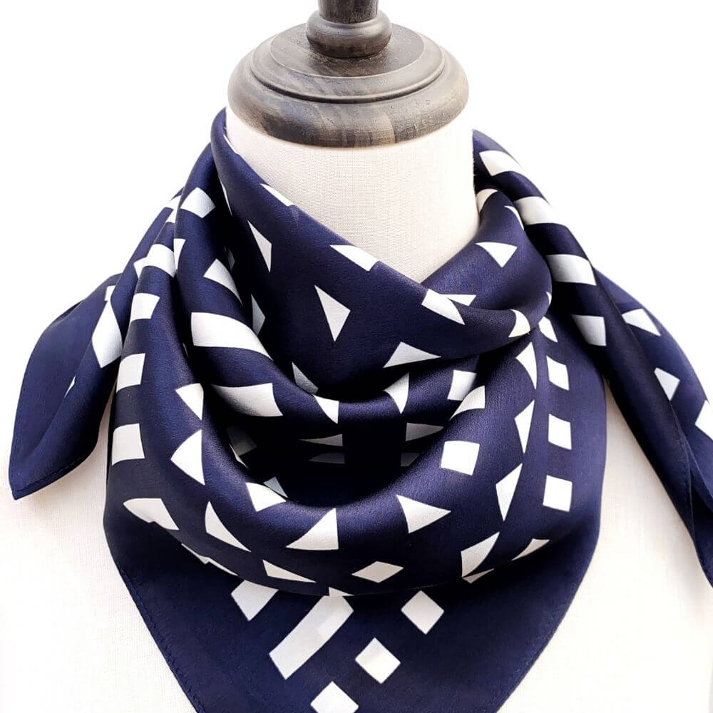 Navy blue silk scarf with white geometric pattern on a mannequin