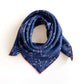 Looped navy mulberry silk bandana scarf showcasing a white geometric pattern and red edges.