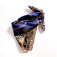 A folded mulberry silk square scarf featuring a navy blue center with gold chain motifs and a leopard print section on a white background.