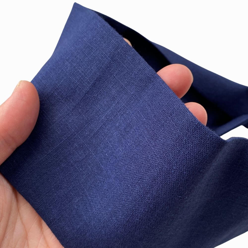 Hand holding a navy blue headband against a white background