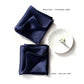 Two navy blue silk scarf, one with a machine-finished hem and the other with a hand-rolled hem, on a white background.