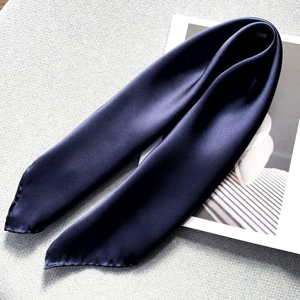 Navy blue silk scarf on a textured surface