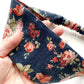 navy rose floral-patterned headband held by a hand with a white background