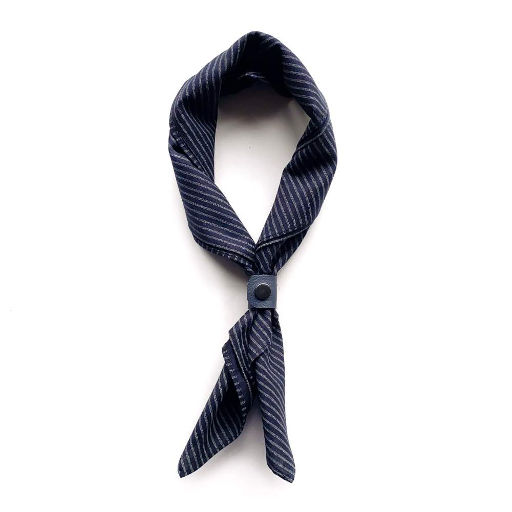 Navy striped scarf tied with a leather scarf clip on a white background