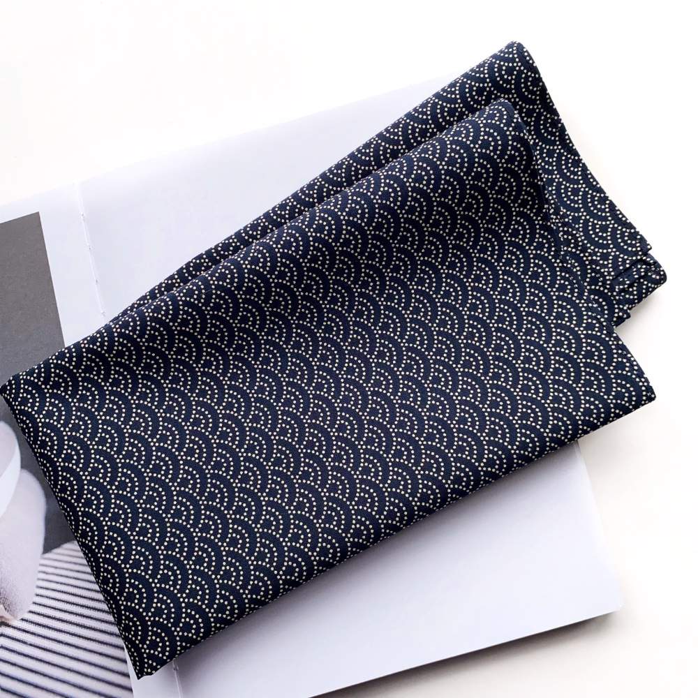 folded navy cotton bandana with white dotted wave pattern on a white surface